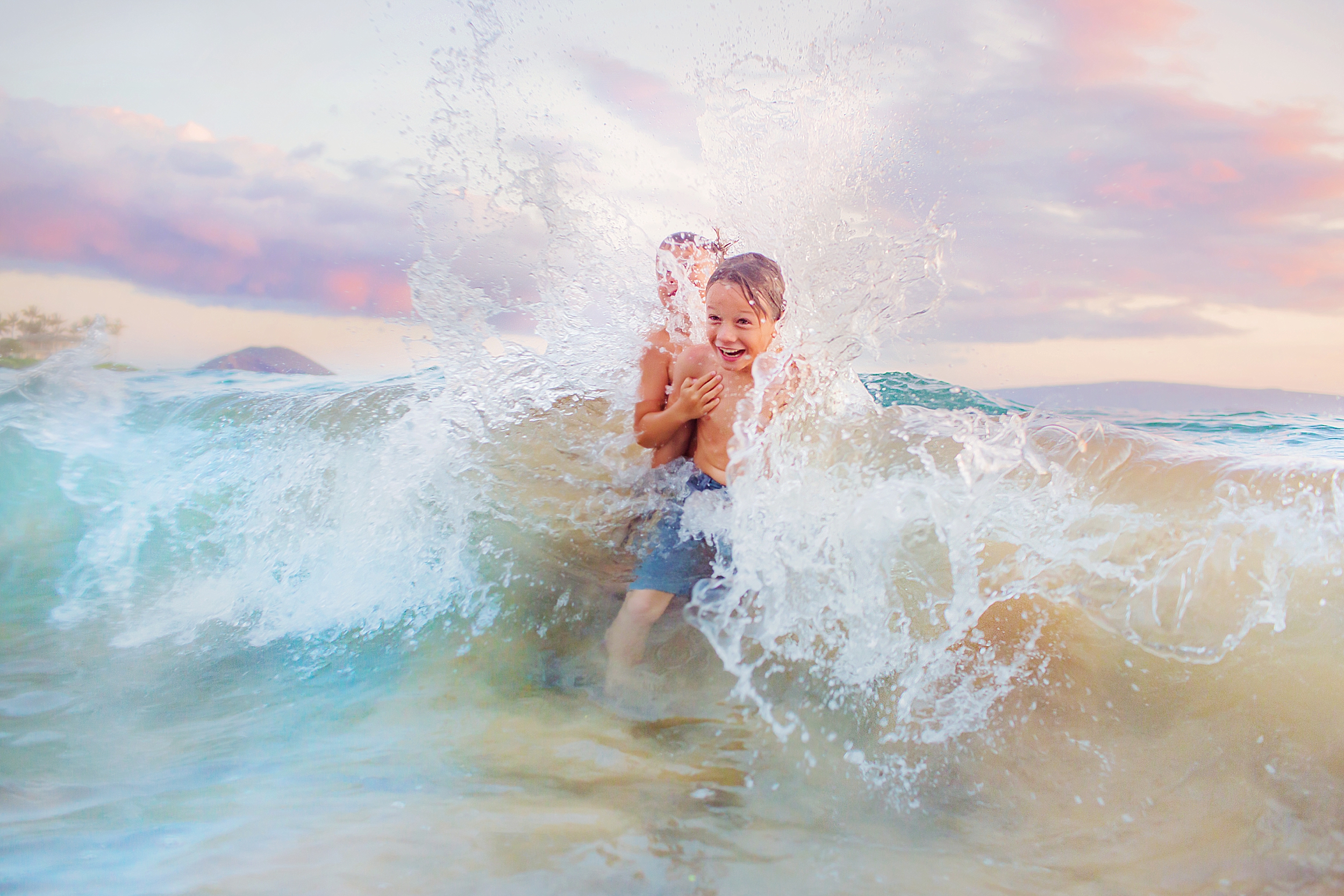 Two boys laugh and splash in the ocean on Maui during their love and water photography session