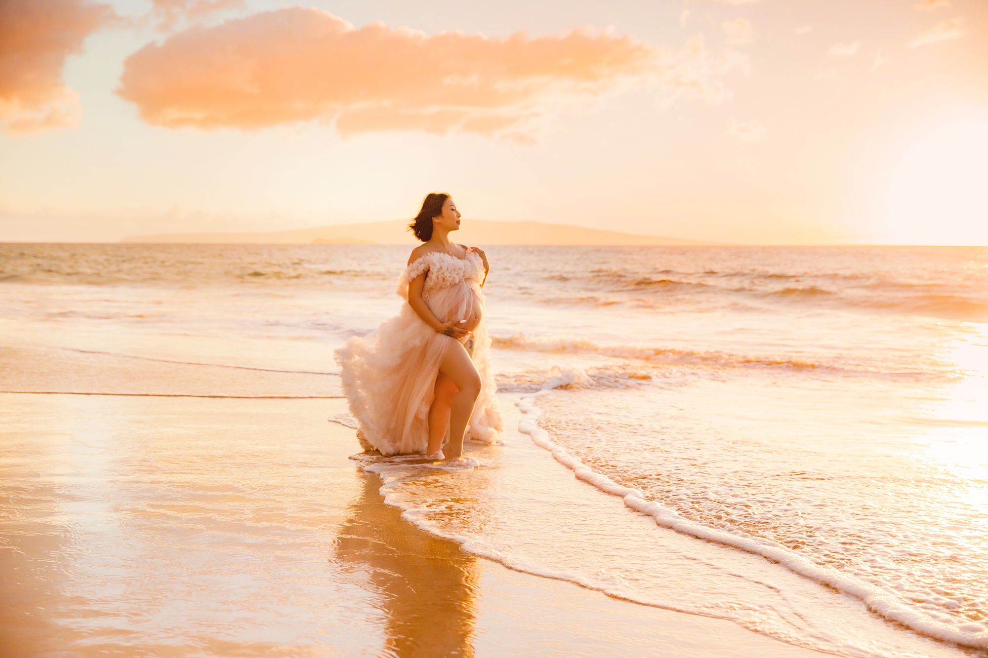 gorgeous pink fluffy maternity gown worn at the beach at sunset