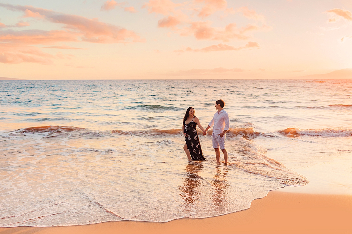 couple holding hands for their beautiful maui babymoon beach portraits with Love + Water