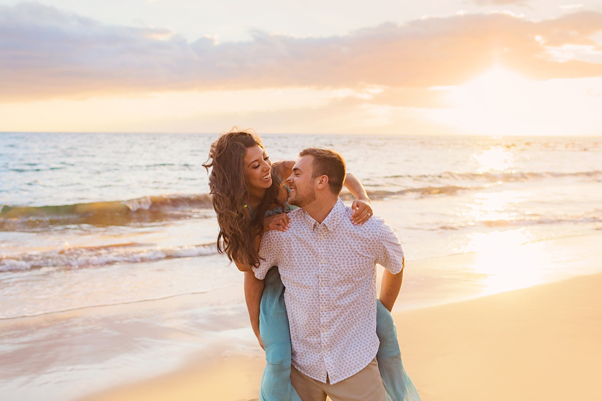 girl piggyback on fiance's shoulders at sunset on the beach in wailea for their engagement session