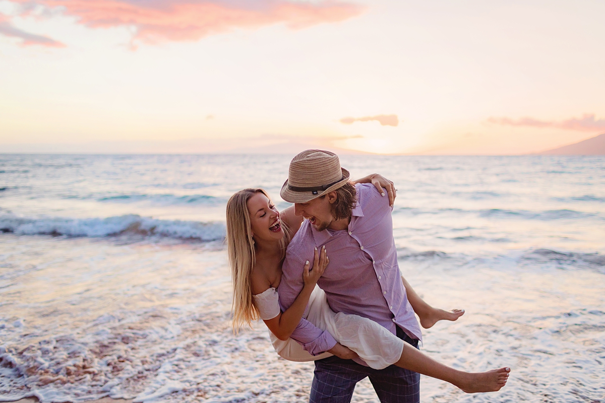 woman piggyback with fiance and laughing near the shoreline at the beach in Wailea