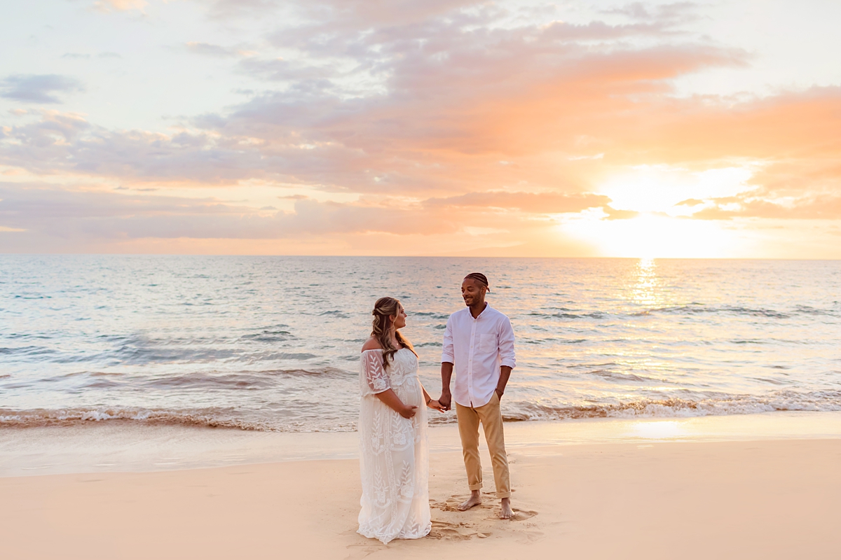 Husband and wife holding hands during sunset Maui maternity session