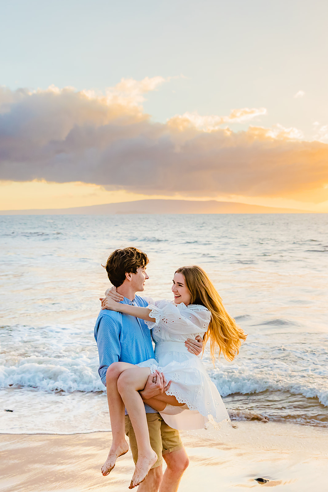 Influencer Mia Maples smiles at her fiance as he twirls her around on for beach engagement photos with Love + Water Photography in Maui.