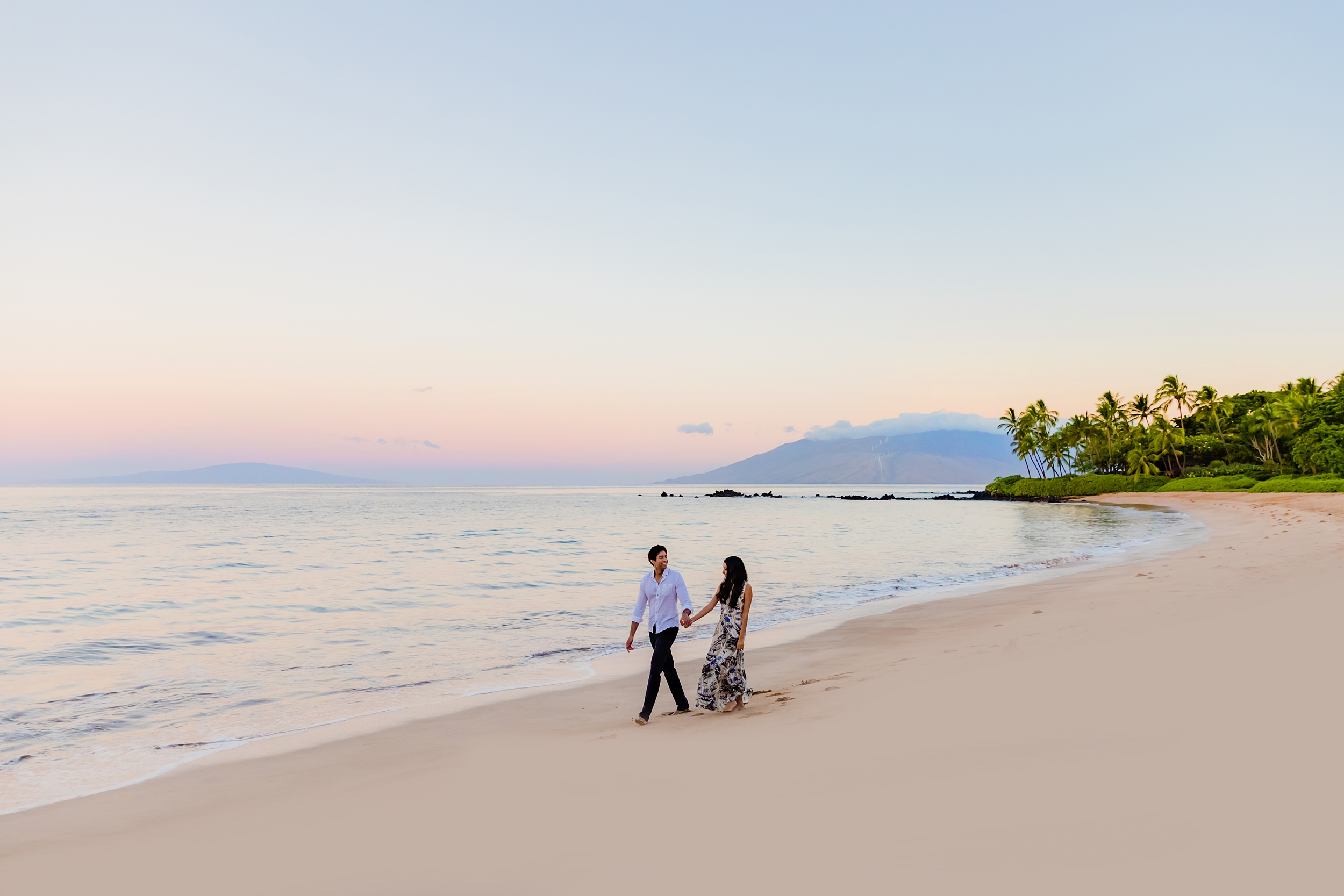 Couple walks hand-in-hand down the beach at sunrise in Wailea before the boyfriend proposes on the beach.