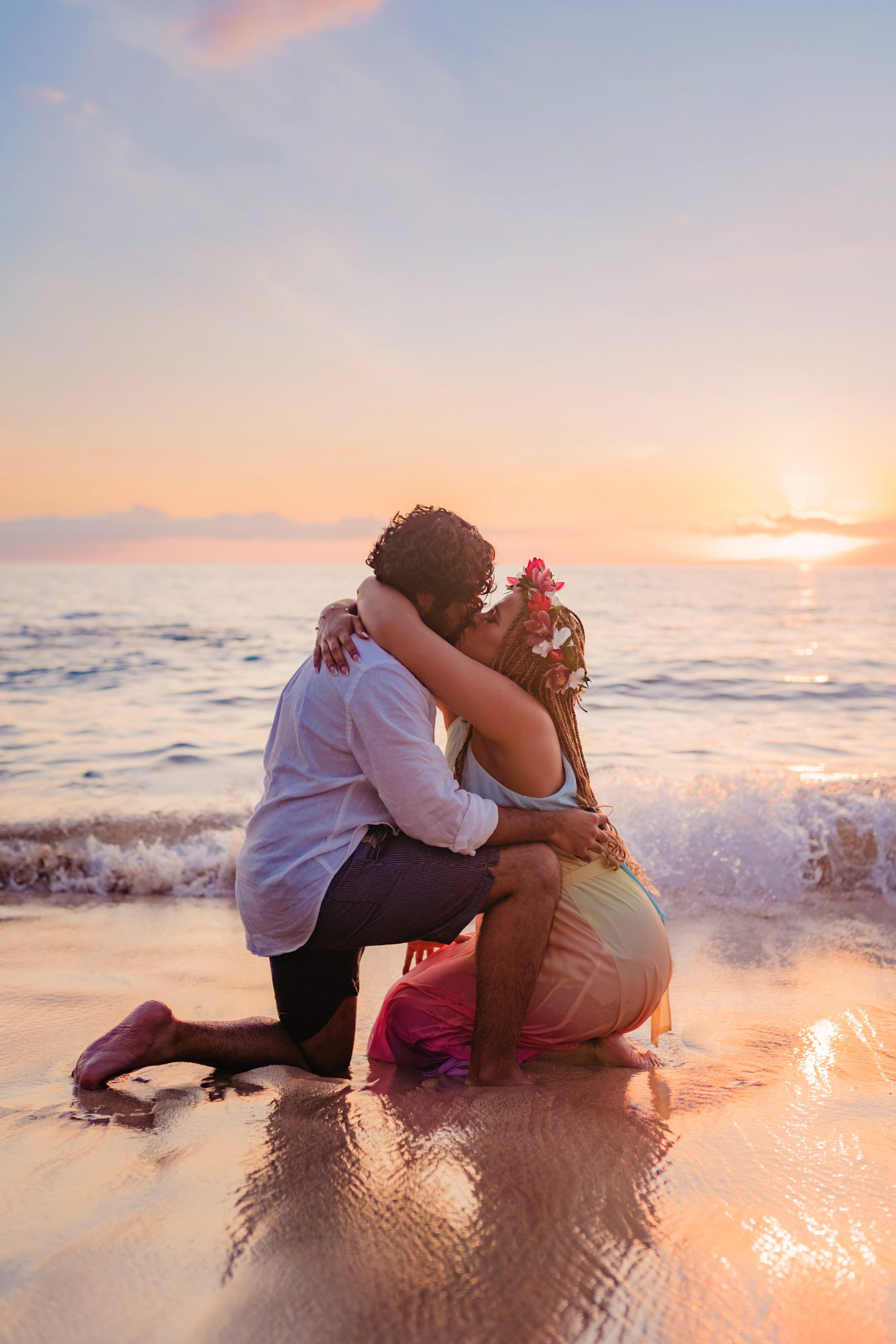 Maui surprise proposals photographed by Love and Water featruring a woman on her knees kissing her boyfriend in at the beach at sunset in Wailea.