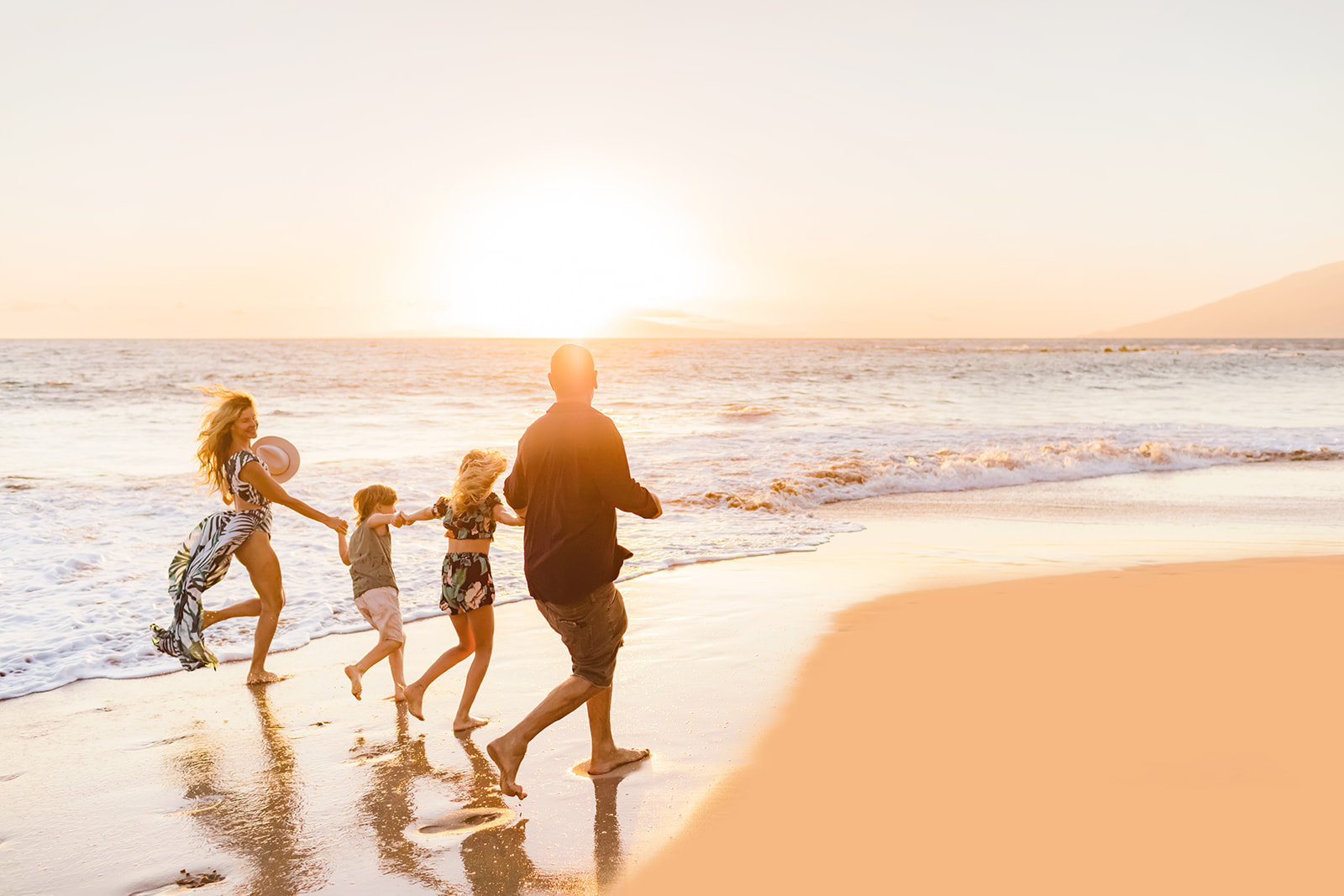 a family running on the beach together for sunset family beach photos on Maui, an eco-friendly activity in Hawaii.