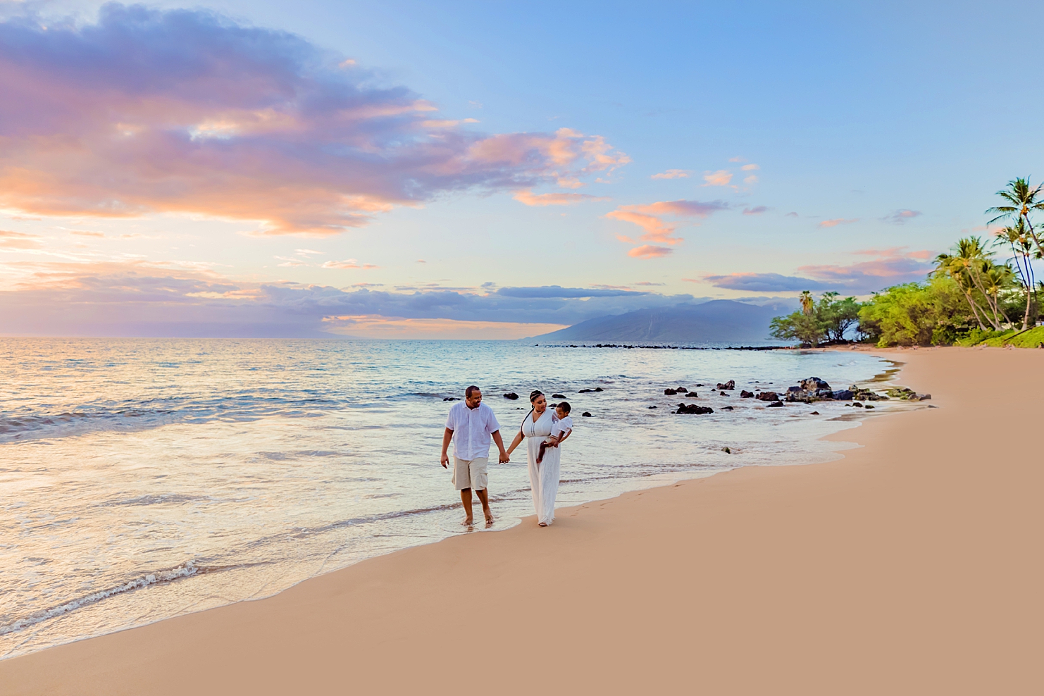 beach photoshoot ideas hawaii featuring family of three holding hands and walks along the beach at sunset in wailea