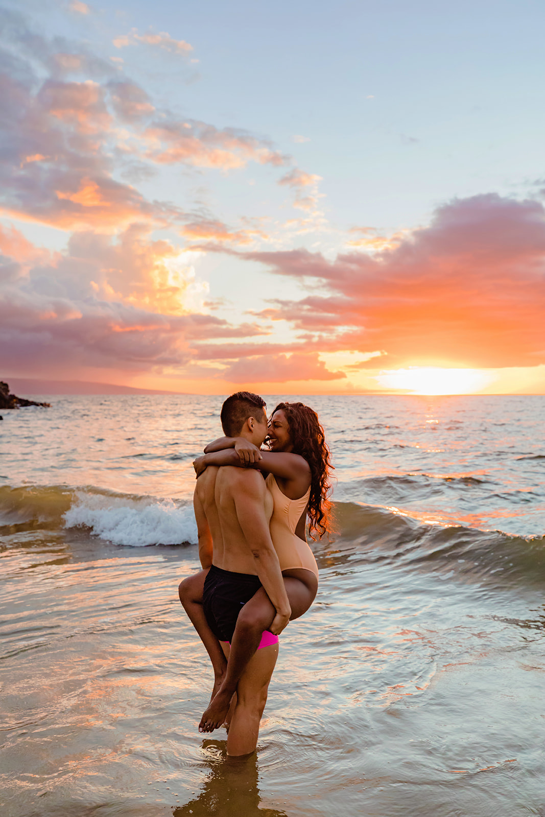 woman wraps her arms around her husband and laughs at sunset