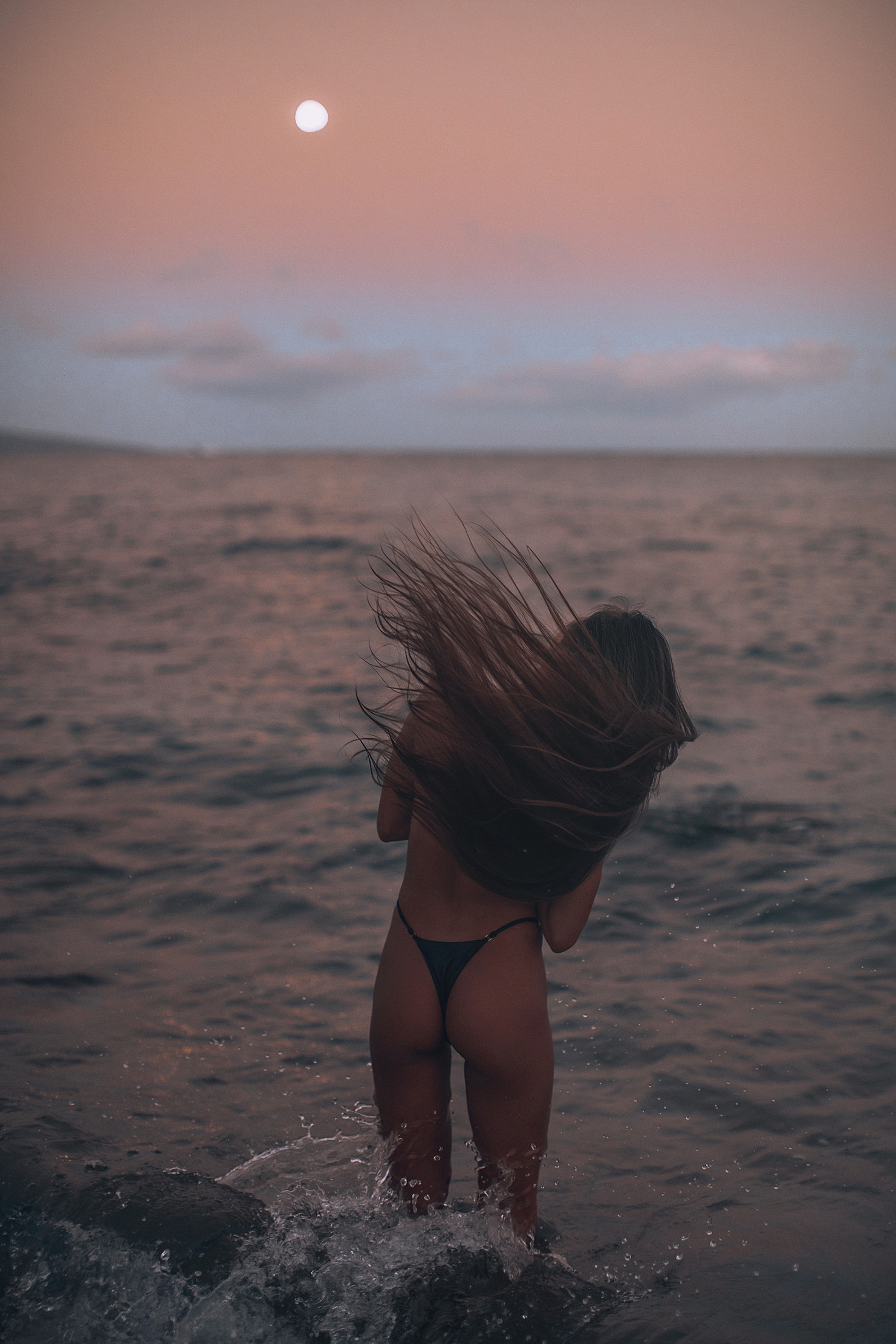 ideas for a full moon photography session featuring young woman with long brown hair tossing her head in the waves in maui