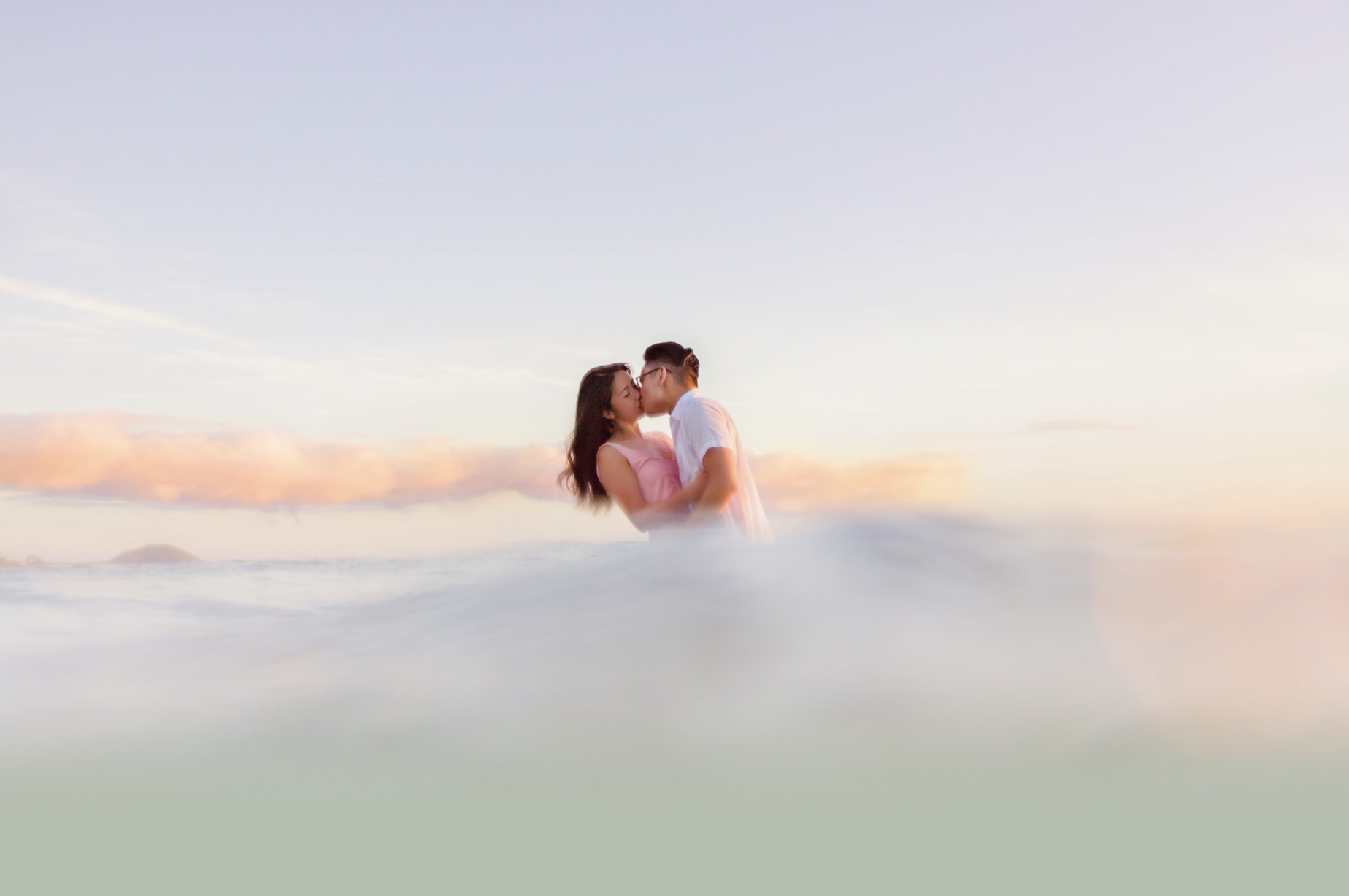 couple embraces in the ocean during their engagement session in hawaii by love and water