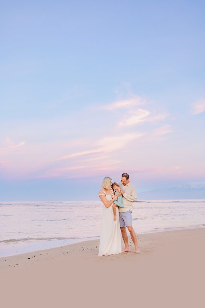 lahaina maui family photography session at sunrise in maui, hawaii with pastel skies and mom wearing a white gown
