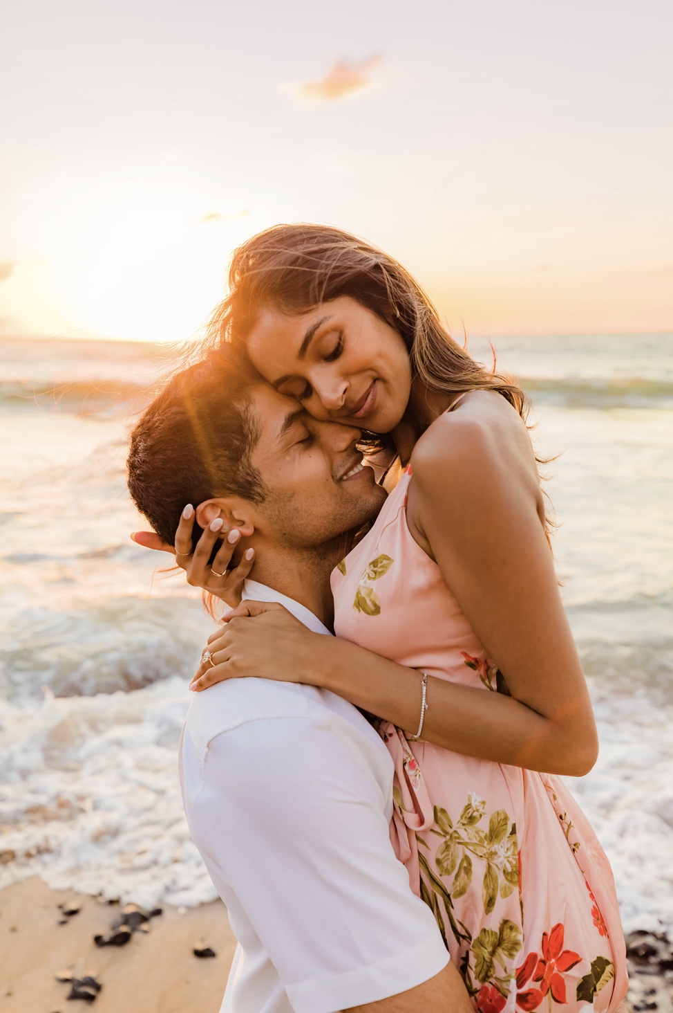 newly engaged couple snuggles on the beach at sunset in maui