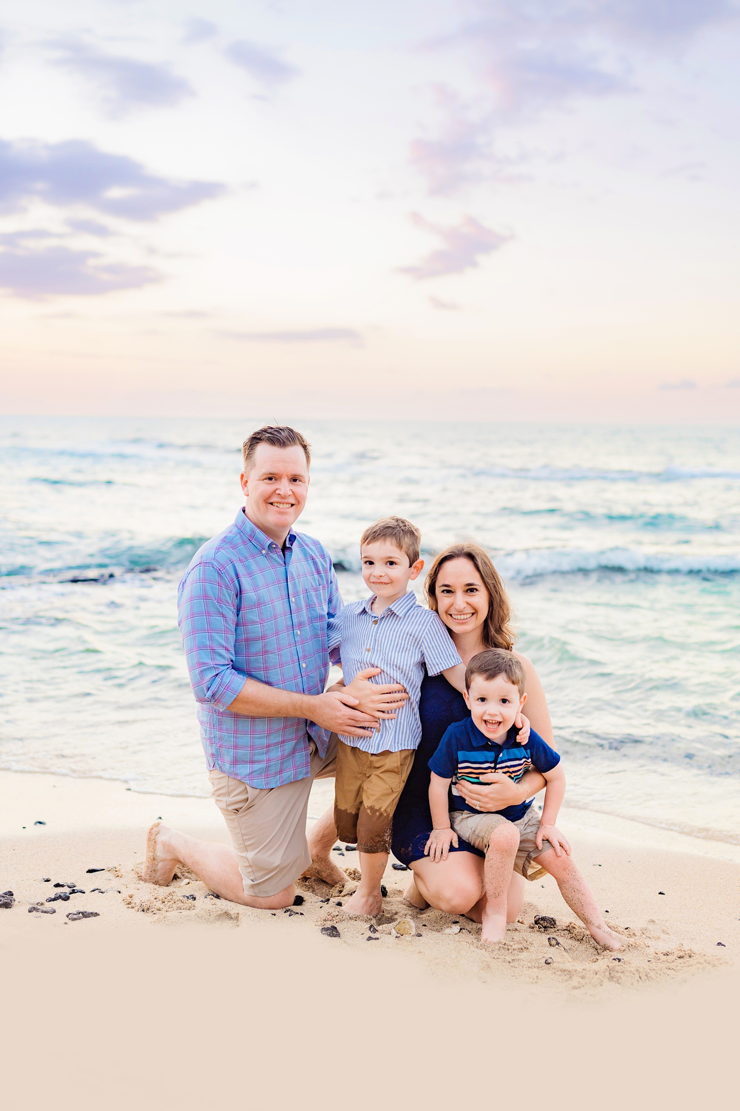 family of four with two young boys looks at the camera and smiles for their waikoloa family portraits
