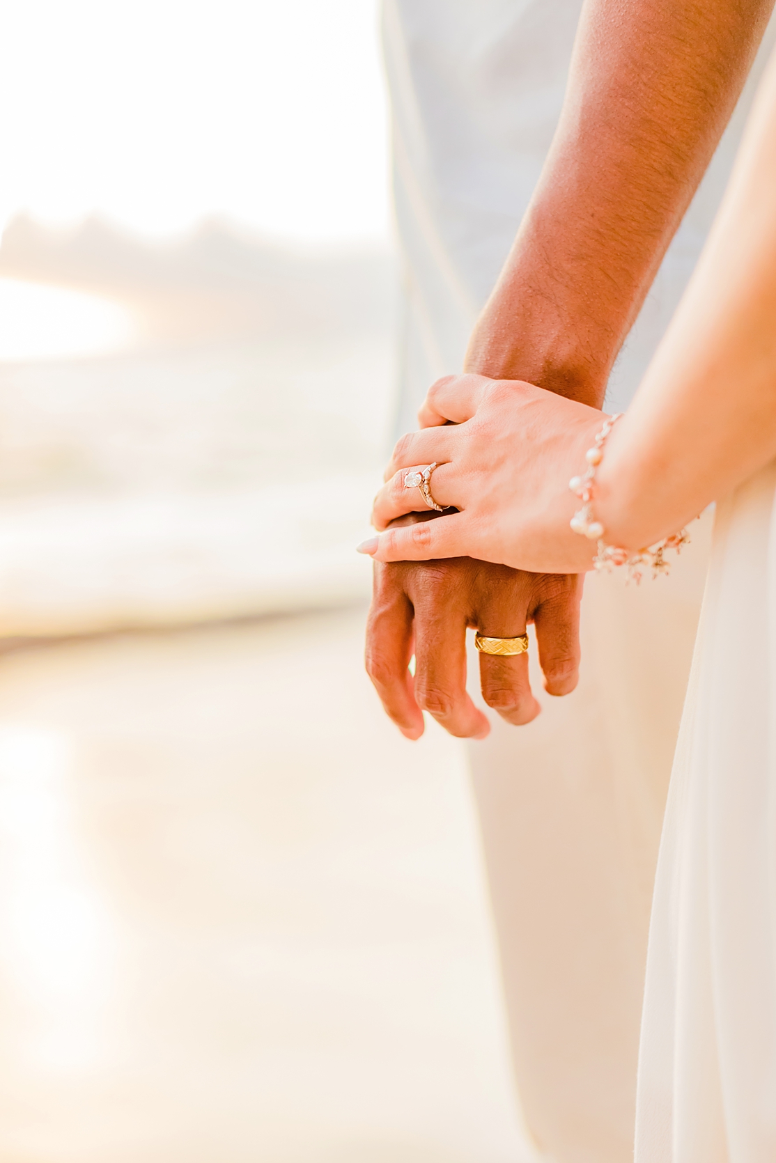 close up photograph of couple holding hands with wedding bands facing camera