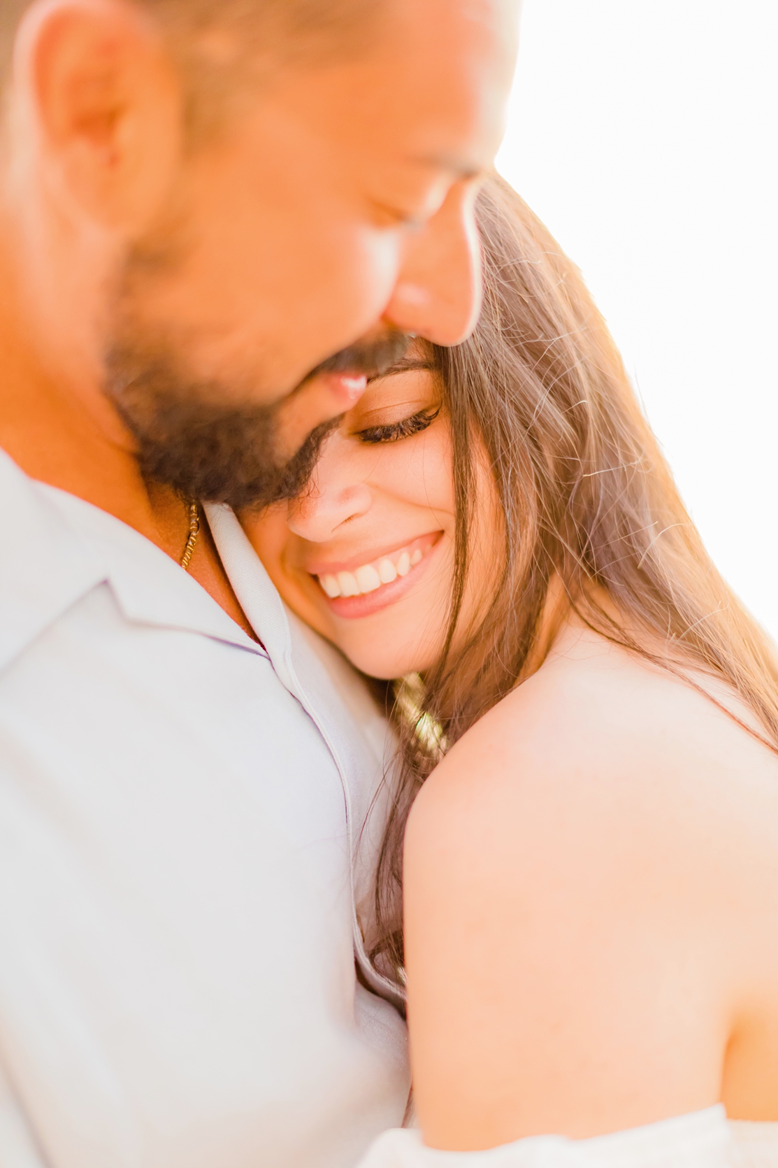 Close up image of couple during their honeymoon on Maui, woman with beautiful smile closing eyes cuddling in to her husband's chest