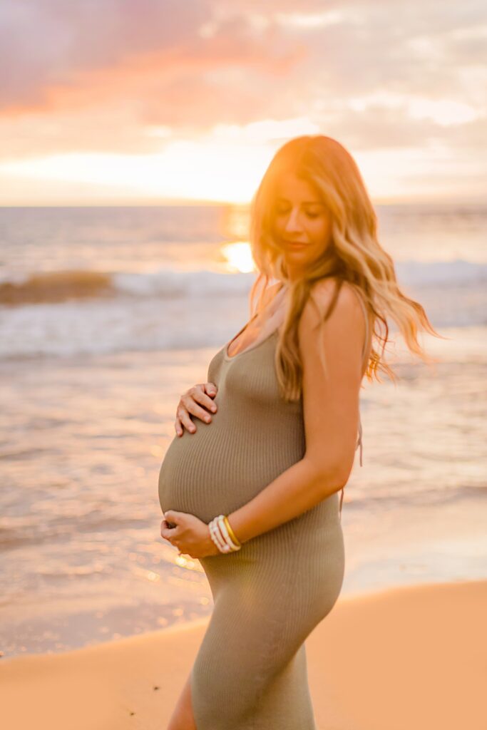 intentionally blurry pregnancy portrait of woman looking down and twirling on the beach for her maui maternity pictures at sunset