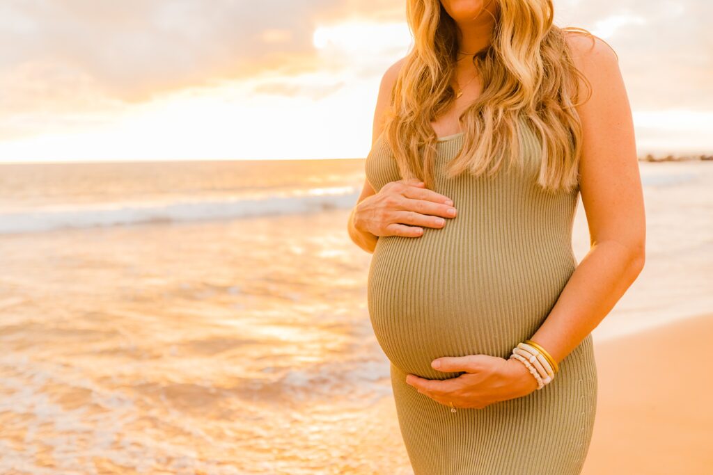 close up of pregnant belly with woman wearing a green stretchy maternity dress