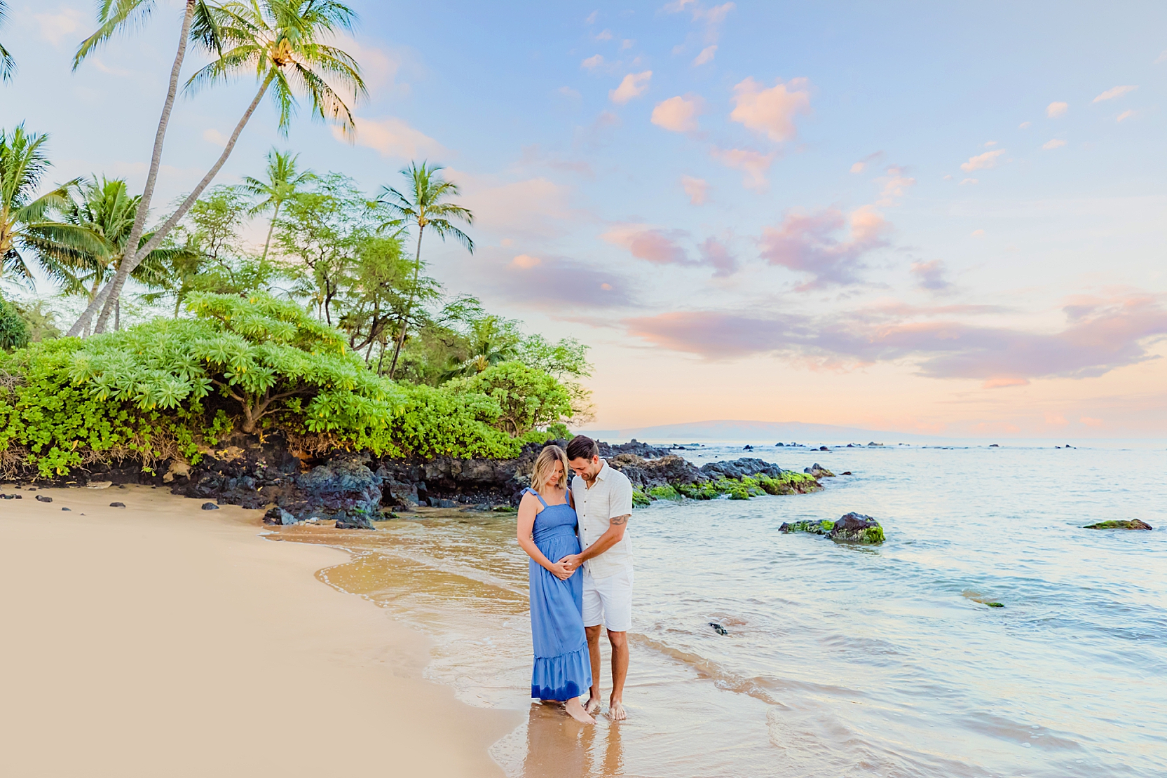 sunrise portrait of pregnant woman wearing a blue gown with husband on the beach in hawaii