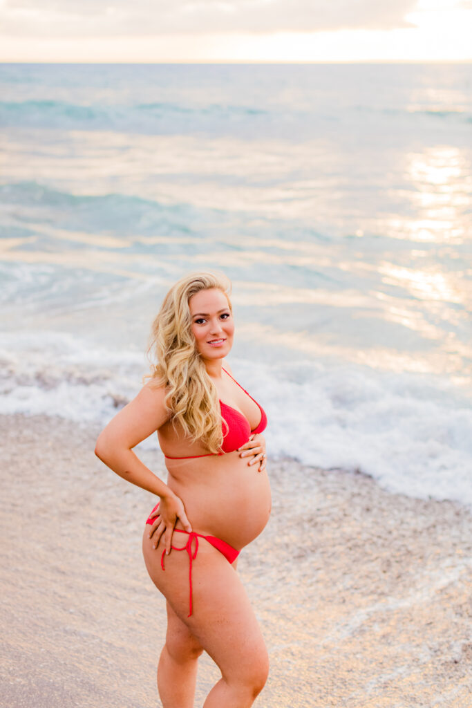 Woman caresses her bump during her babymoon in Maui at her sunset maternity photoshoot
