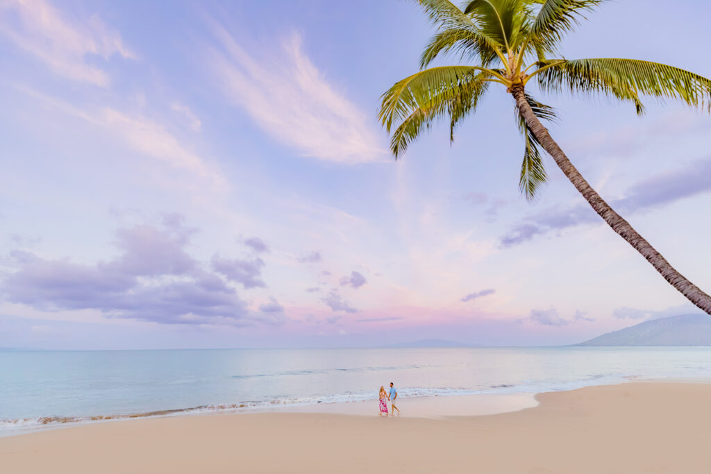 Expecting couple strolls on the beach in Maui as captured by their maternity photographer
