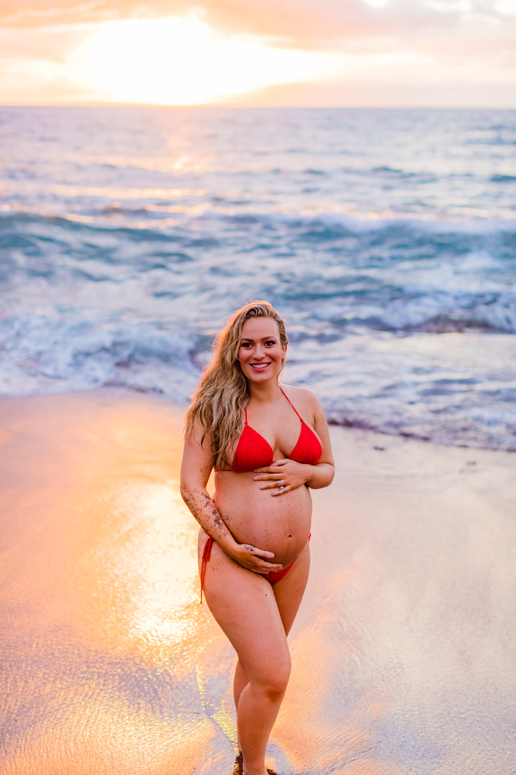 Woman smiles as she poses for her pregnancy photos in Maui during her sunset photoshoot