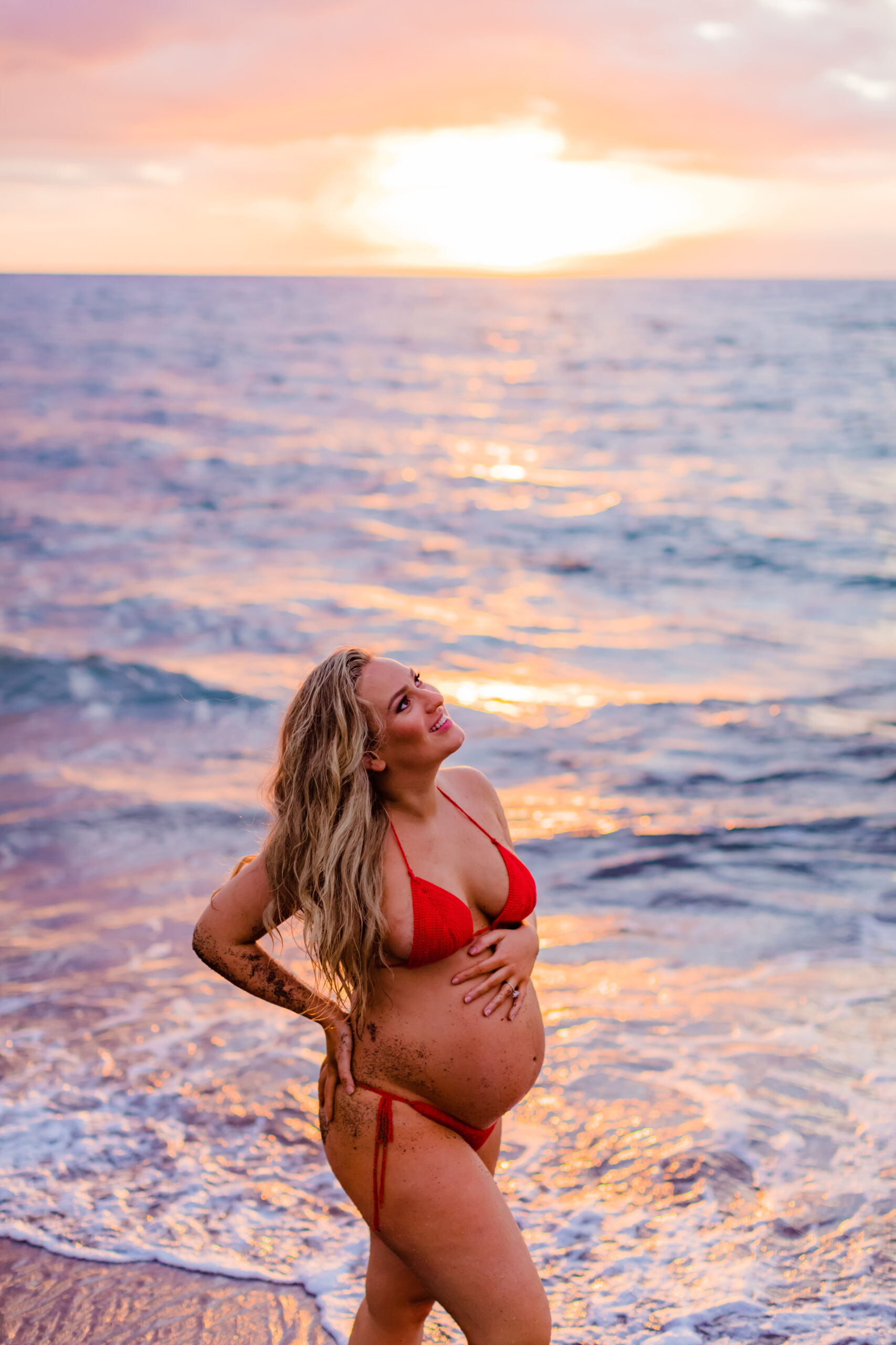 Beautiful pregnant woman smiles as she poses for her maternity photos in Maui during her sunset photoshoot