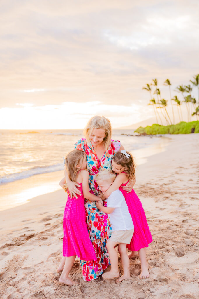 Three kids share a hug with their mom on the beach during their family photoshoot