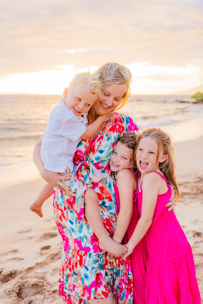 Woman embracing her three kids captured by their family photographer on Maui