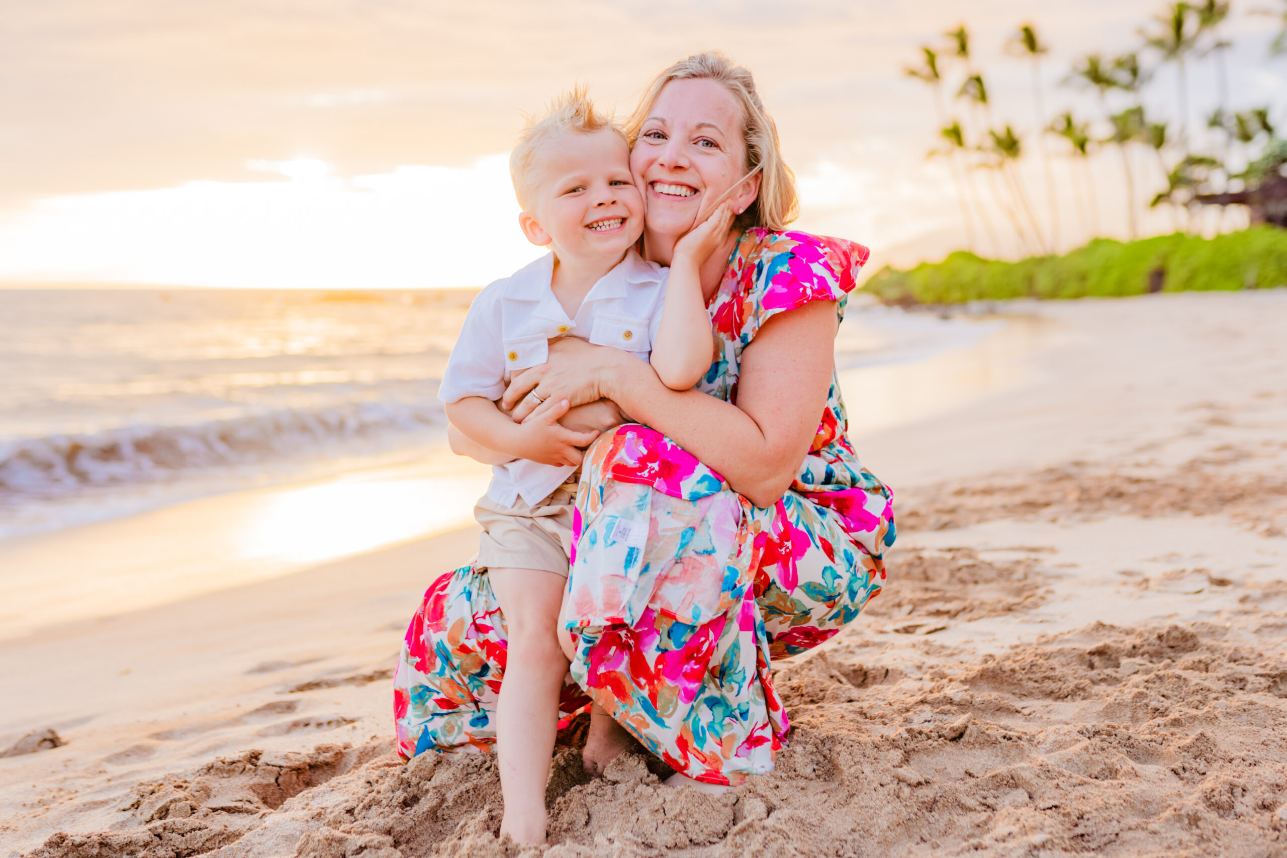 Woman and her son flash a smile to the camera on the beach at sunset