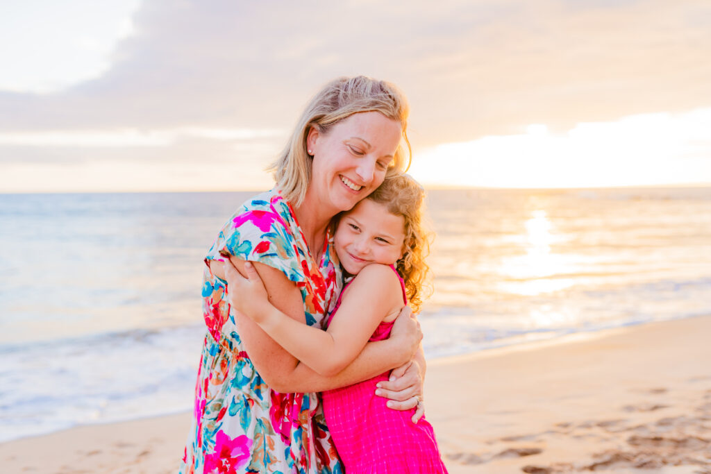 Mom embraces her daughter for a sweet moment during their sunset beach family session