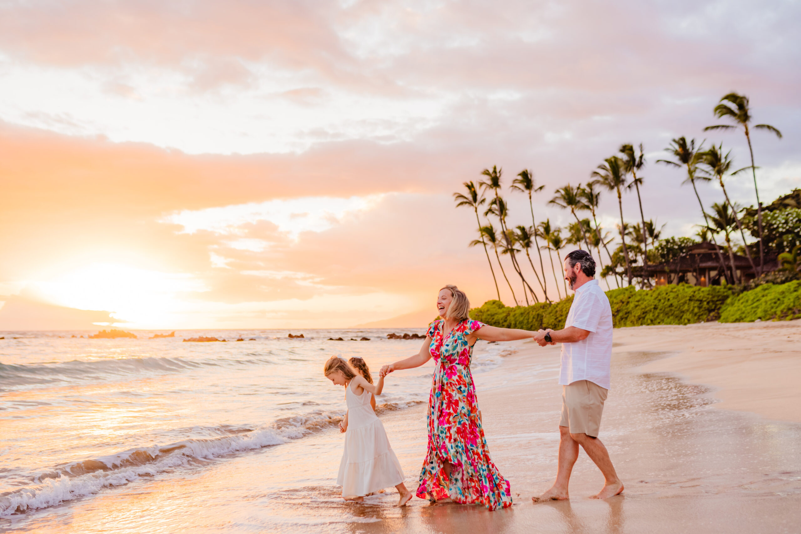 Mom is led towards the water at sunset by her family during a family photoshoot