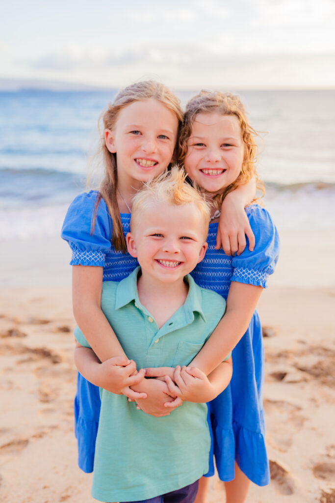 Three kids flash a smile to their Wailea photographer during their beach family photoshoot