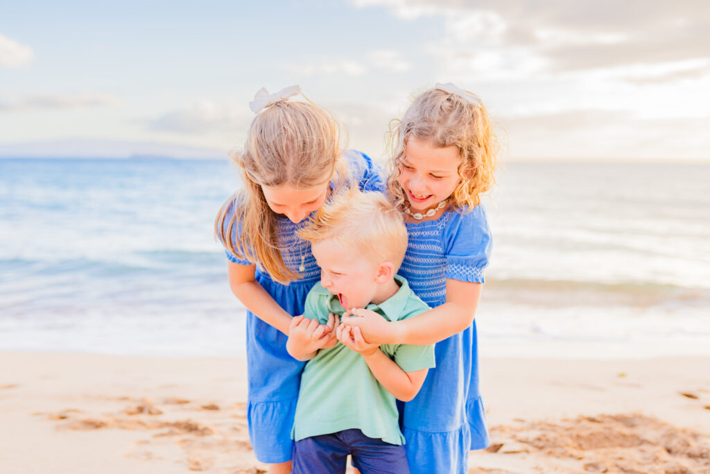 boy is tickled by his older sisters during their family photoshoot on Maui