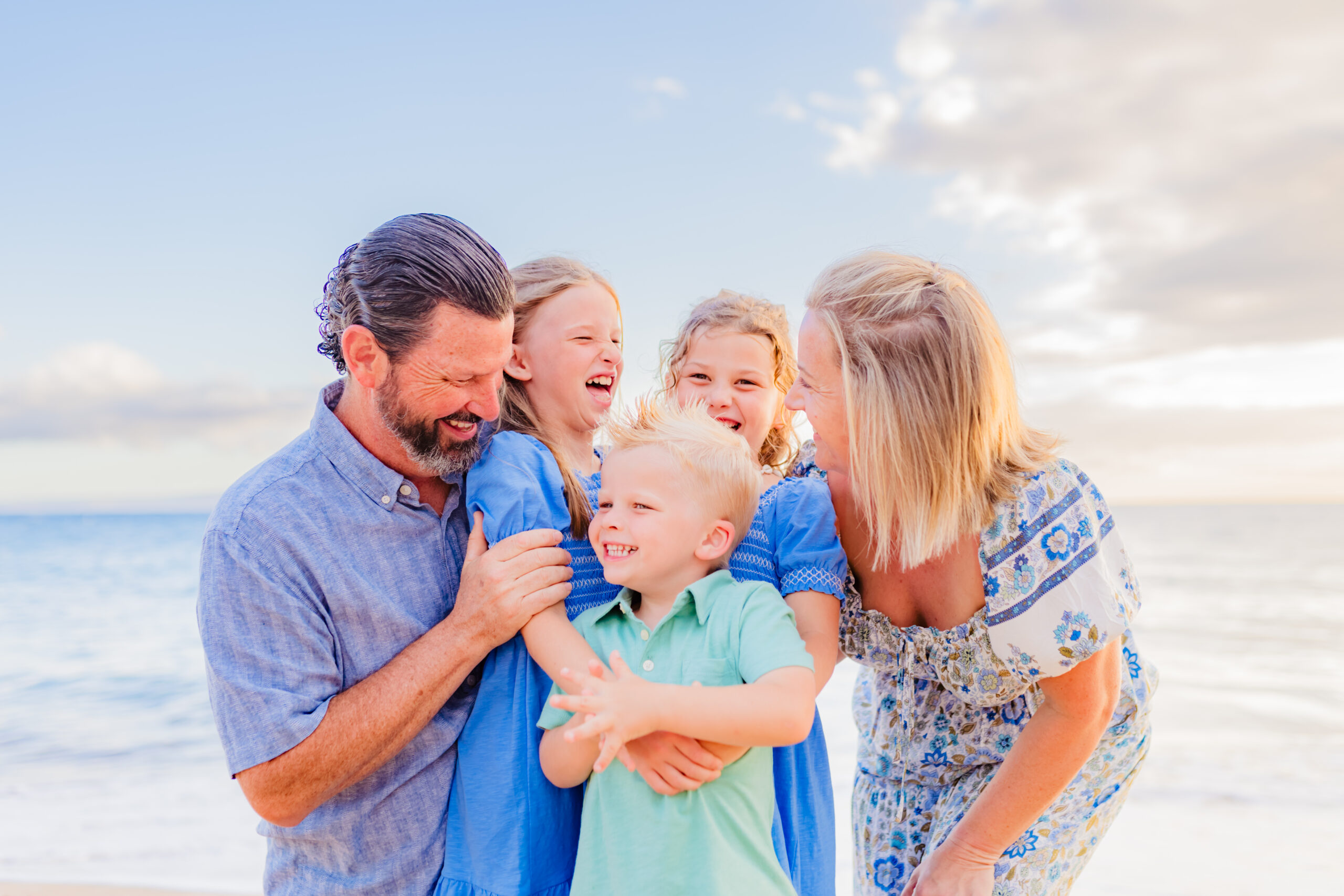 family of five shares a happy moment on Wailea during their sunset beach family photos