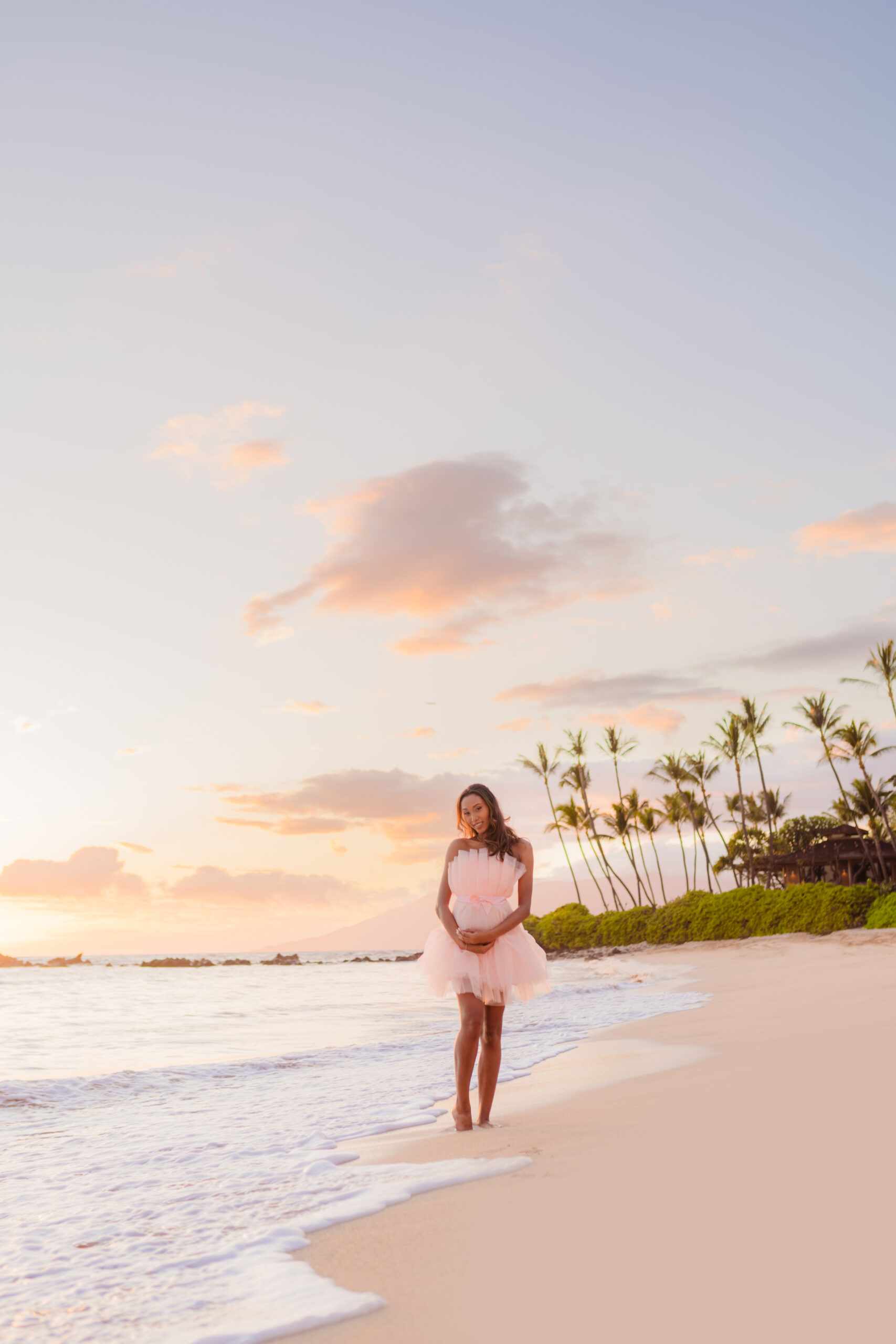 Woman wears a stunning maternity dress for portraits taken during her Maui babymoon