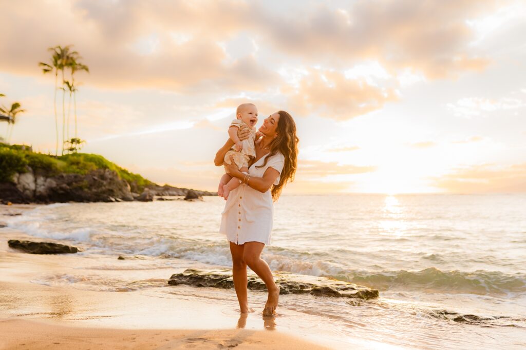 Mom laughs and smiles as her young son grins off camera at dad during Love and Water Photography shoot in West Maui