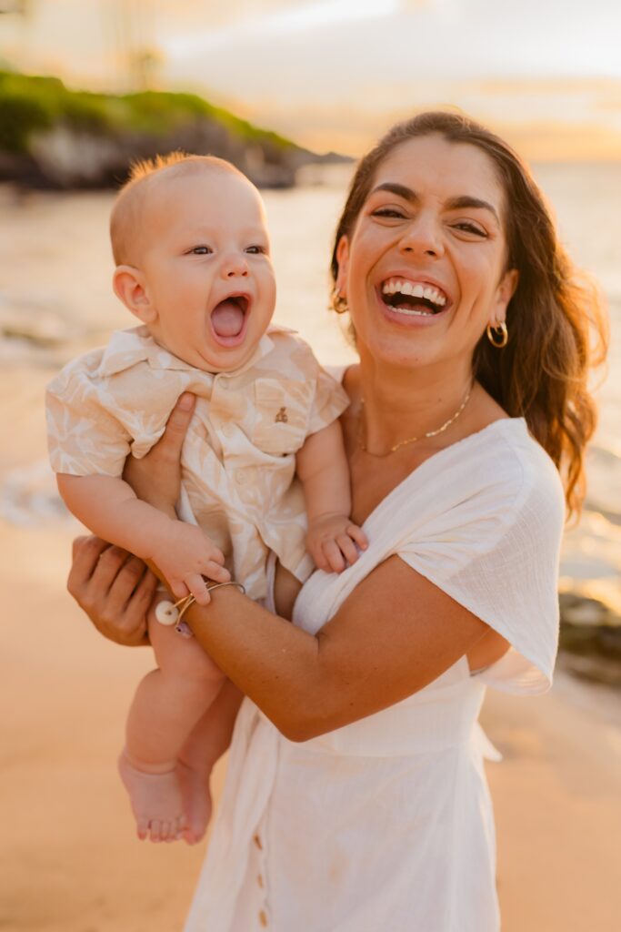 Maui family portrait session by Love and Water featuring young brunette mom holding infant son smiling and laughing at camera