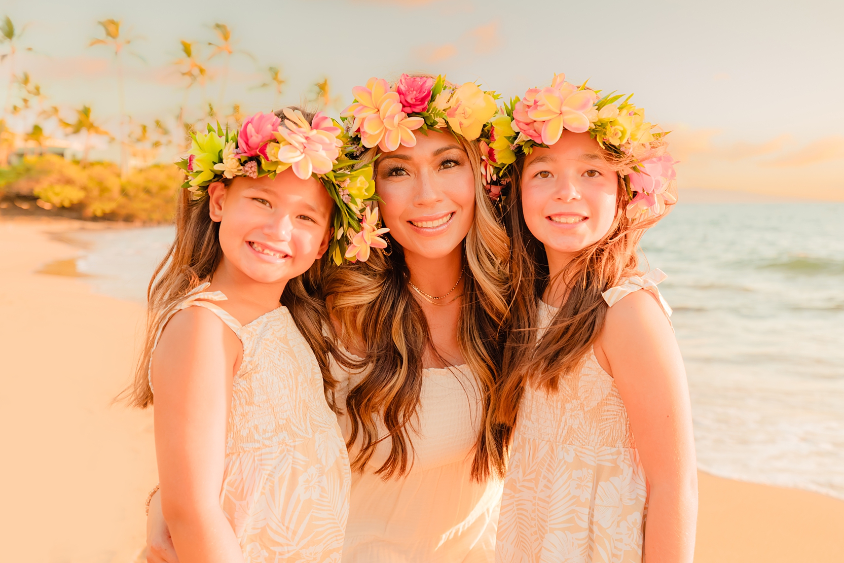 Mother and two young daughters wearing matching lei po'o or flower crowns on the beach during their Hawaii family photos with Love. and Water