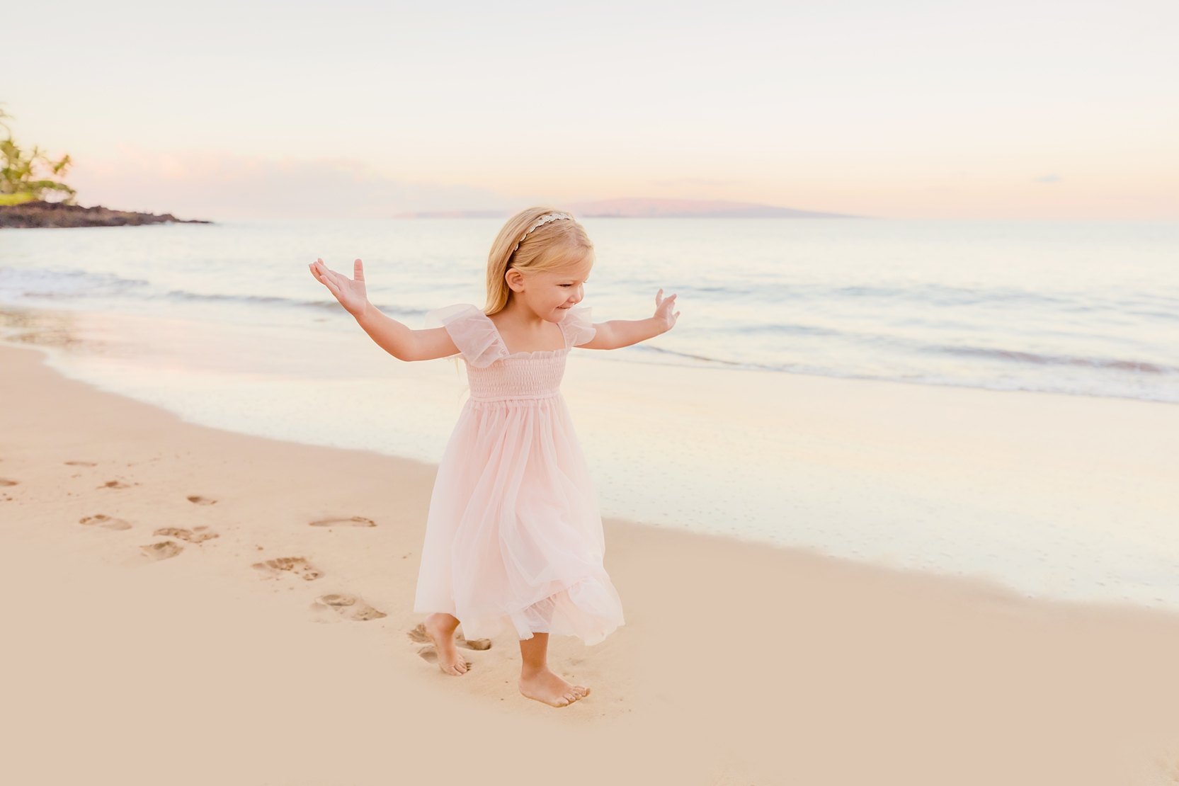 young girl in pink dress runs on the beach at sunrise during maui family photos on the beach by love and water