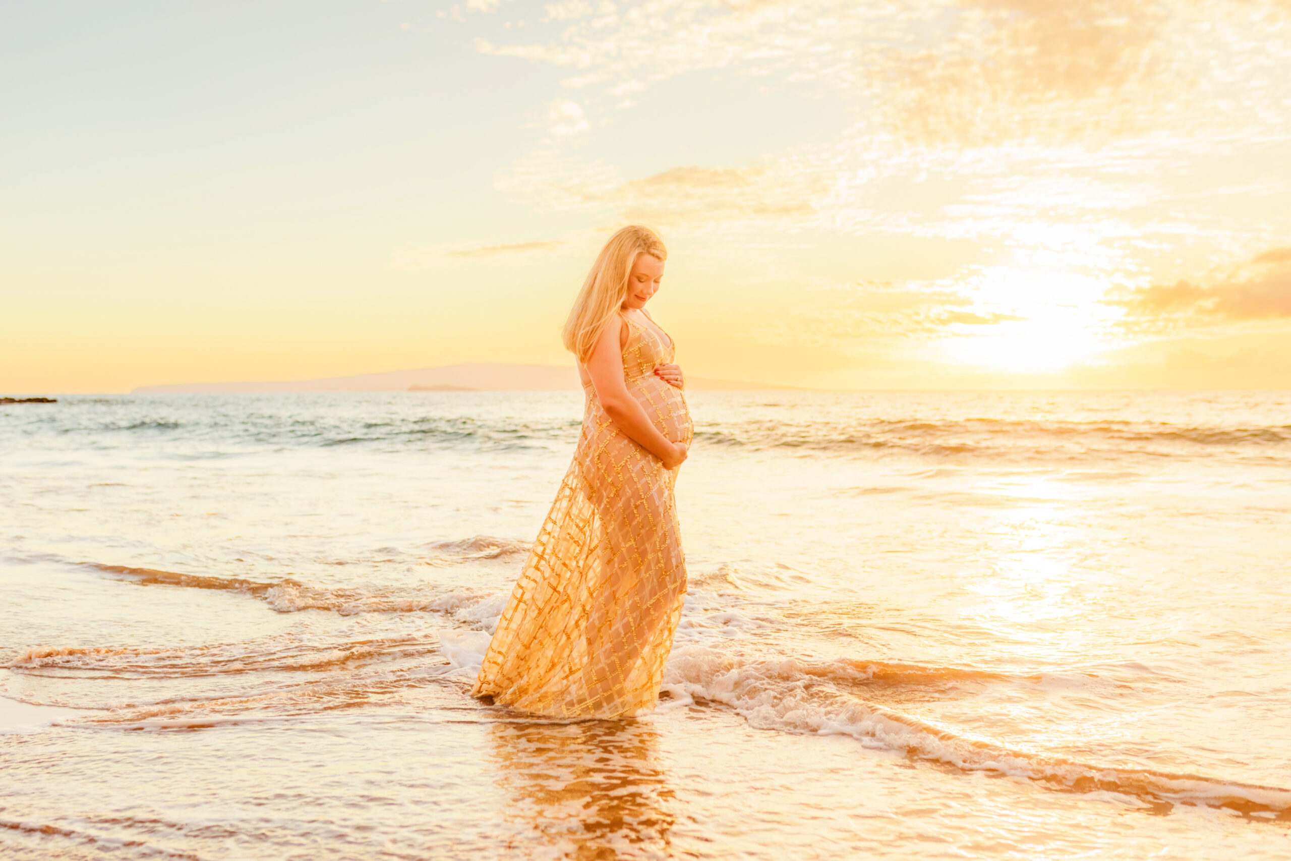 pregnant woman in hawaii at the beach in the waves during photoshoot