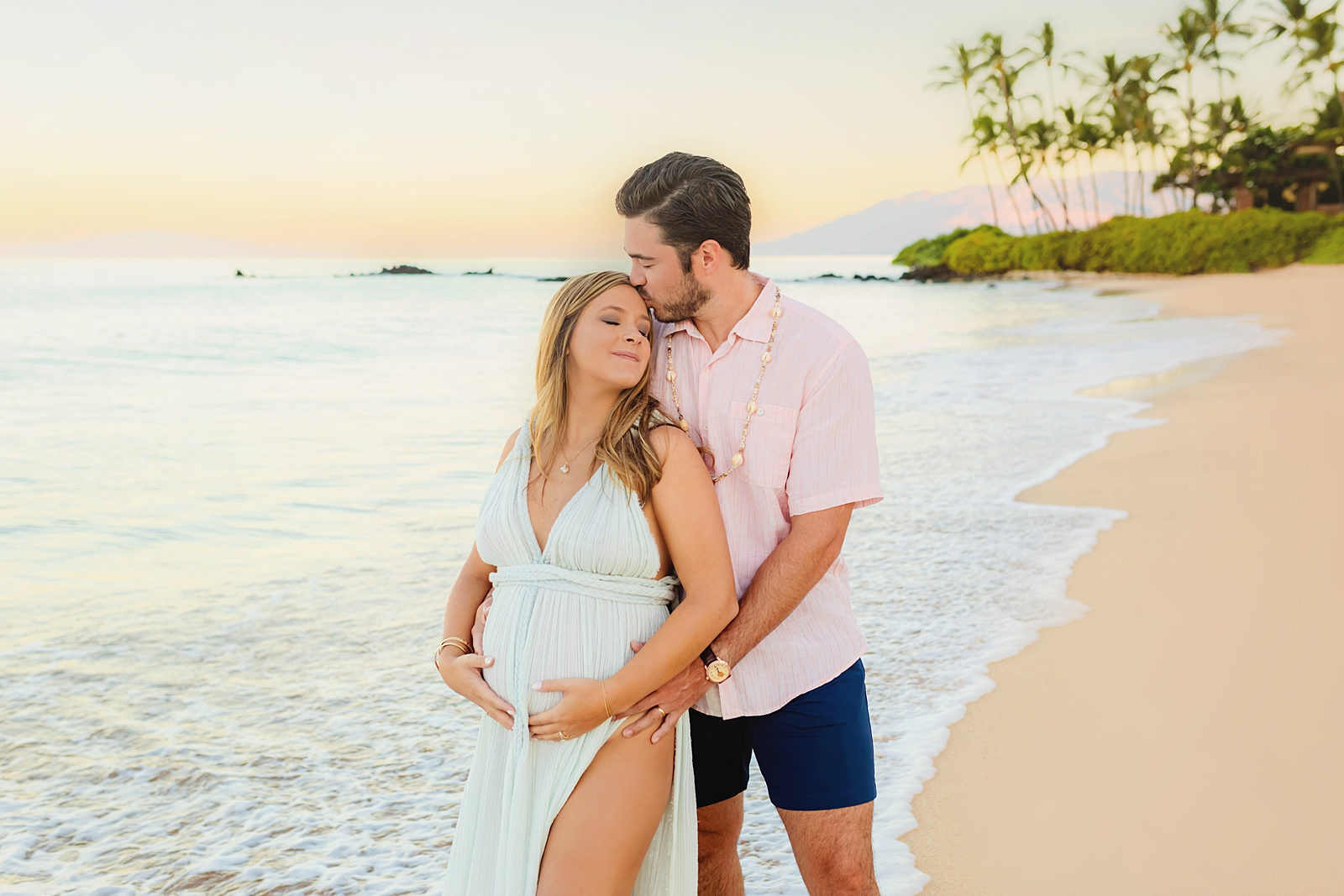 A couple standing together on the beach for maternity photos on Maui, Hawaii.