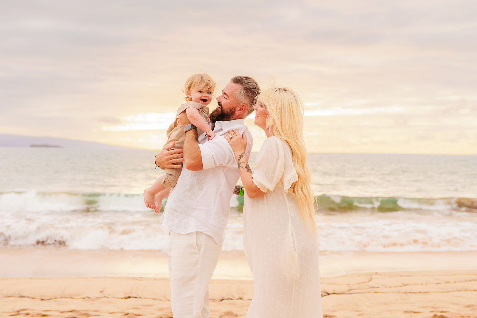 A family playing together on the beach for a sunset maternity photoshoot with a toddler in Wailea on Maui with Love + Water photography.