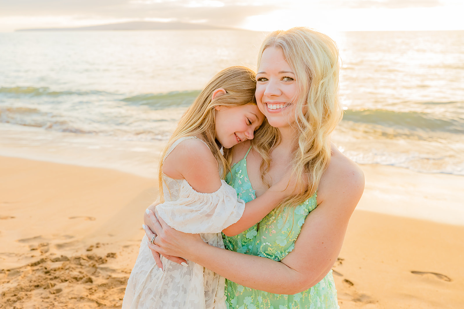mother and daughter hugging on the beach in maui hawaii at sunset during a photoshoot