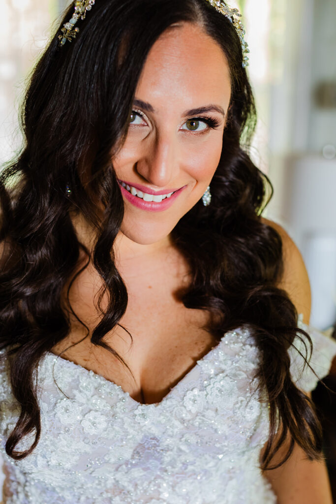 A beautiful bride with long brown hair smiles while preparing to walk down the aisle for her maui wedding at Olowalu Plantation House in hawaii.