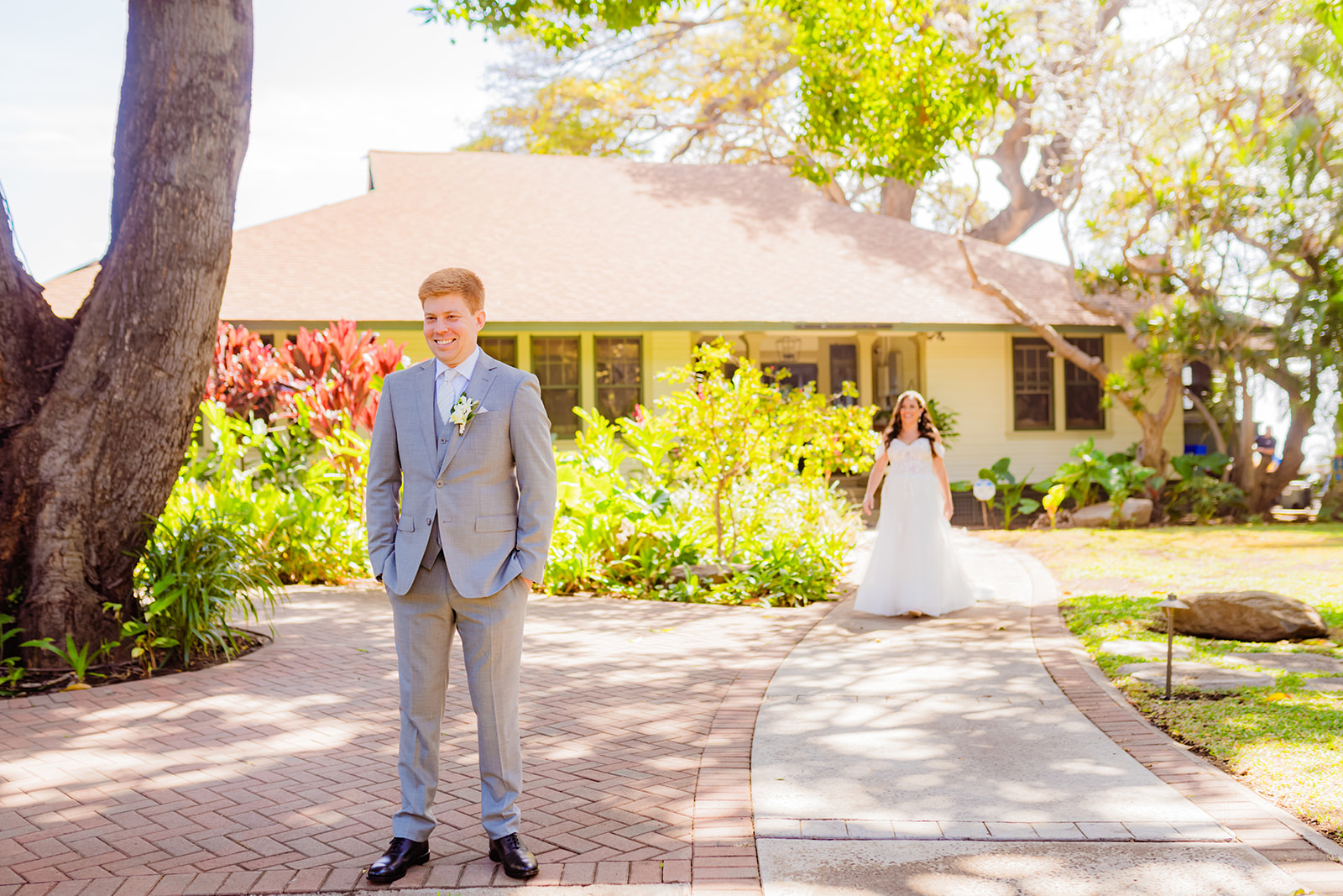 A bride approaches her groom from behind to surprise him for a first look before their maui wedding while love + water wedding photography captures the moment.