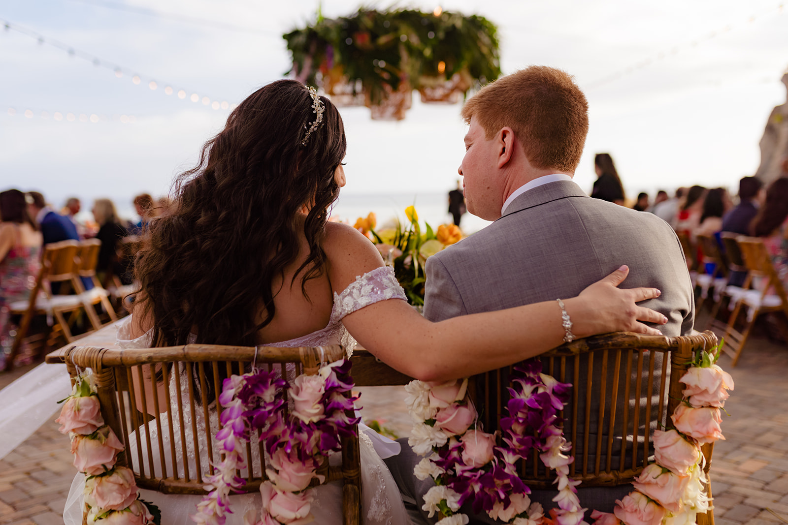 A bride and groom sit together at the head table at a beautiful maui wedding venue, Olowalu Plantation House.