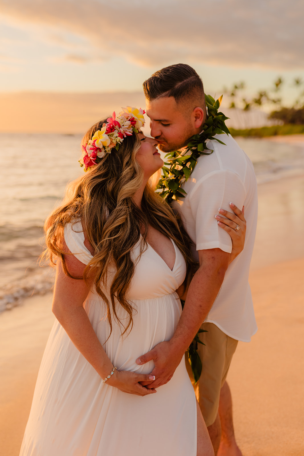 A man and woman holding each other during a  sunset maternity photoshoot on maui at the beach with love + water photography. 