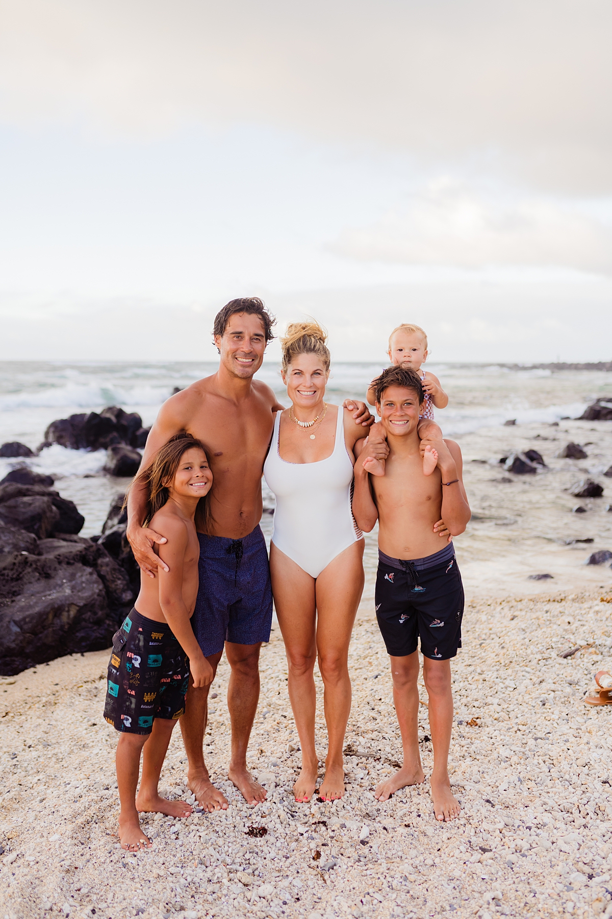 A family of five cuddling together on the sand during a Maui portrait session.