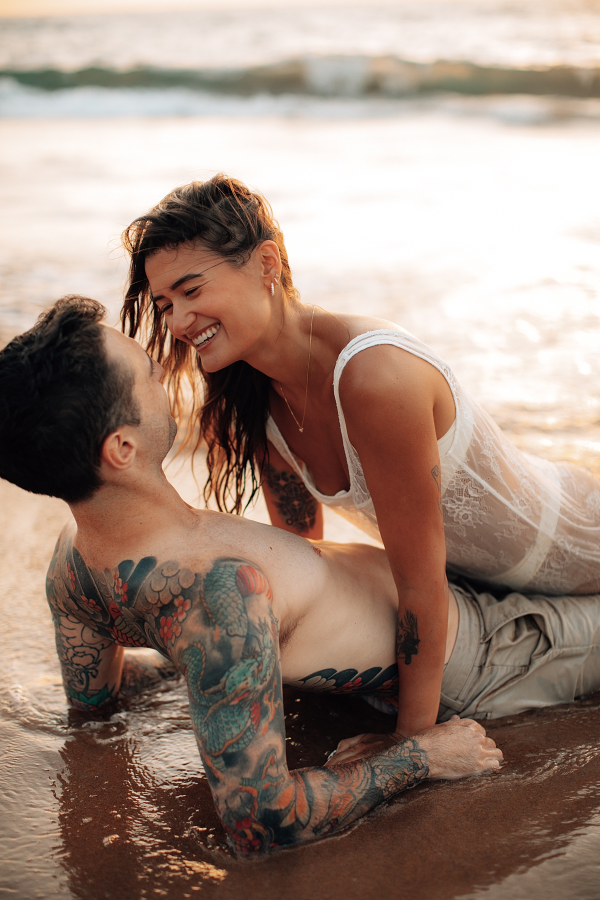 Close-up of a couple gazing into each other’s eyes while lying on the beach sand in Wailea, Maui.