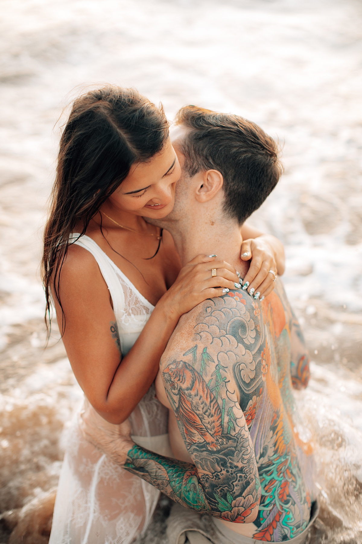 Candid shot of a couple laughing together while rolling on the warm sands of Wailea Beach at sunset.